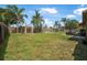 Fenced backyard featuring a shed, palm trees, patio set, and ample green space at 1191 Tracy Dr, Port Orange, FL 32129