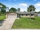 Charming single-story home featuring a lush green lawn, a palm tree, and an attached garage at 1191 Tracy Dr, Port Orange, FL 32129