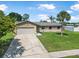 Charming single-story home featuring a lush green lawn, a palm tree, and an attached garage at 1191 Tracy Dr, Port Orange, FL 32129