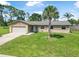Charming single-story home featuring a lush green lawn, a palm tree, and an attached garage at 1191 Tracy Dr, Port Orange, FL 32129