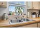 Kitchen sink with stainless steel faucet fixture and window view of a palm tree at 1191 Tracy Dr, Port Orange, FL 32129