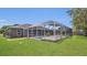 Spacious backyard featuring a screened-in pool, lush lawn, and mature trees for privacy at 1194 Balfour Dr, Deltona, FL 32725