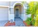 Inviting front entrance with an arched doorway, gray door, brick walkway and palm tree at 12079 Alder Branch Loop, Orlando, FL 32824