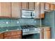 Modern kitchen with granite countertops, mosaic backsplash, stainless steel appliances, and dark wood cabinetry at 12079 Alder Branch Loop, Orlando, FL 32824