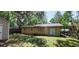 The backyard shows the exterior of a tan home surrounded by mature trees at 1621 Anniston Ave, Daytona Beach, FL 32117