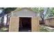 Exterior view of the shed with opened doors, with shelving inside, and backyard trees surrounding at 1621 Anniston Ave, Daytona Beach, FL 32117