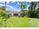 Sprawling backyard with well-maintained lawn, a screened-in patio, and tropical foliage at 1653 Promenade Cir, Port Orange, FL 32129