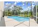 Enclosed pool with cage overlooking lush landscaping and blue skies at 1653 Promenade Cir, Port Orange, FL 32129