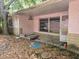 Overgrown back porch area featuring broken windows, piles of leaves, and damaged exterior walls at 16880 Se 63Rd Ln, Ocklawaha, FL 32179