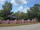 Home featuring a pink block fence, mature landscaping, and a view of the house at 16880 Se 63Rd Ln, Ocklawaha, FL 32179