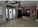Spacious living room features french doors, a brick wall, tile floors, and built-in shelves at 16880 Se 63Rd Ln, Ocklawaha, FL 32179