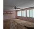 Living room with large windows, a ceiling fan, built-in shelving and worn flooring at 16880 Se 63Rd Ln, Ocklawaha, FL 32179