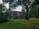 Backyard with mature trees, a fenced pool area, and a two-story house, surrounded by lush greenery at 1725 Turtle Hill Rd, Enterprise, FL 32725