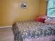 This cozy bedroom has light yellow walls, a neutral toned bedspread and a window to the yard at 1725 Turtle Hill Rd, Enterprise, FL 32725