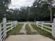 View of driveway entrance framed by a white fence and decorative post lamps at 1725 Turtle Hill Rd, Enterprise, FL 32725