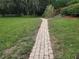 Landscaped front yard featuring a brick paver walkway, decorative grasses, and mature shade trees at 1725 Turtle Hill Rd, Enterprise, FL 32725