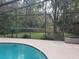 View of the enclosed pool area with a glimpse of the serene backyard through the screened enclosure at 1725 Turtle Hill Rd, Enterprise, FL 32725