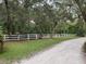 Gravel road alongside the property's boundary, defined by a well-maintained white fence at 1725 Turtle Hill Rd, Enterprise, FL 32725