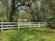 View of the lush, expansive property with white fencing and mature, moss-draped trees at 1725 Turtle Hill Rd, Enterprise, FL 32725