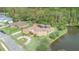 Aerial view of a home with solar panels, landscaping, pond, and circular driveway at 18 Foxfords, Ormond Beach, FL 32174