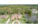 Aerial view of house with lake, solar panels, circular driveway, and lush landscaping at 18 Foxfords, Ormond Beach, FL 32174