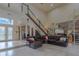 Open-concept living room with a large leather sofa and spiral staircase, providing seamless flow and a welcoming atmosphere at 18 Foxfords, Ormond Beach, FL 32174