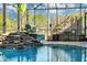 View of enclosed pool area boasts a striking rock waterfall feature complemented by lush plantings and comfortable seating at 19343 Moorgate St, Orlando, FL 32833