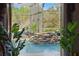 Beautiful in-door pool with rock waterfall feature with a view of the greenery outside at 19343 Moorgate St, Orlando, FL 32833