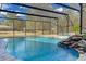 View of this enclosed pool shows a picturesque rock waterfall feature against a backdrop of open skies and lush greenery at 19343 Moorgate St, Orlando, FL 32833