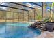 Pool area shows a soothing rock waterfall, enhanced by lush greenery, creating a serene and inviting backyard oasis at 19343 Moorgate St, Orlando, FL 32833