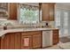 Well-lit kitchen featuring granite countertops, wood cabinets, and stainless steel dishwasher at 2004 Quail Hollow Dr, Deland, FL 32720