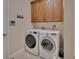 Convenient laundry room with modern washer and dryer, overhead cabinets, and neutral decor at 2004 Quail Hollow Dr, Deland, FL 32720