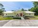 Charming single-story home featuring a covered porch, red doors, and manicured landscaping on a sunny day at 2953 Sled Rd, Christmas, FL 32709