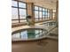 Brightly lit indoor pool area featuring a hot tub, tile flooring, and large windows offering a pleasant view at 3003 S Atlantic Ave # 17A1, Daytona Beach Shores, FL 32118