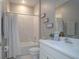 This bathroom features a shower and tub combination, white tiled walls, and a sleek white vanity and sink at 3026 Adrian Dr, Ormond Beach, FL 32174