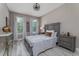 Cozy bedroom featuring wood-look tile floors, two windows, and furniture in neutral tones at 3026 Adrian Dr, Ormond Beach, FL 32174