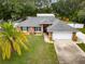Aerial view of brick home with large yard, palm tree and attached two car garage at 3210 Whitehorse Ct, Deltona, FL 32738