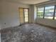 Living room with large windows, door to backyard and worn floors at 327 Frances Ter, Daytona Beach, FL 32118