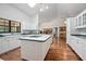 Well-lit kitchen featuring an island cooktop, white cabinets, and hardwood floors at 3357 Black Willow Trl, Deland, FL 32724