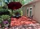 Back patio with an umbrella table set surrounded by greenery and potted flowers at 37 Meadowwood Trl, Deland, FL 32724