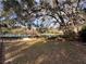A sprawling lawn with mature trees provides serene views of the community pool and tennis courts at 37 Meadowwood Trl, Deland, FL 32724