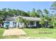 Charming single-story home featuring a covered porch, mature trees, and lush lawn at 3788 Fir Ct, Ormond Beach, FL 32174