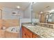 Well-lit bathroom featuring a soaking tub and vanity with a granite countertop at 5300 S Atlantic Ave # 12-403, New Smyrna Beach, FL 32169