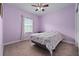 Bedroom with purple walls, carpeted floors, a window, and a bed with a floral patterned comforter at 5513 Estero Loop, Port Orange, FL 32128