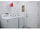 Bright laundry room with washer, dryer, storage shelf, and laundry-themed decor at 5513 Estero Loop, Port Orange, FL 32128
