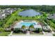 Community pool area with lounge chairs, palm trees, and a lake view in the background at 5513 Estero Loop, Port Orange, FL 32128