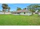 View of the home with a screened-in porch, lush green grass, and mature palm trees at 718 Sleepy Hollow Dr, Port Orange, FL 32127