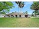 Charming single-story home with a well-manicured lawn, palm trees, and an inviting arched entryway at 718 Sleepy Hollow Dr, Port Orange, FL 32127