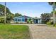 Charming blue home featuring a paved driveway, lush green lawn, and tropical landscaping in the front yard at 809 E 14Th Ave, New Smyrna Beach, FL 32169