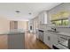 Modern kitchen with white cabinets, stainless steel appliances, and an island, opening to a living space at 825 Wells Dr, South Daytona, FL 32119